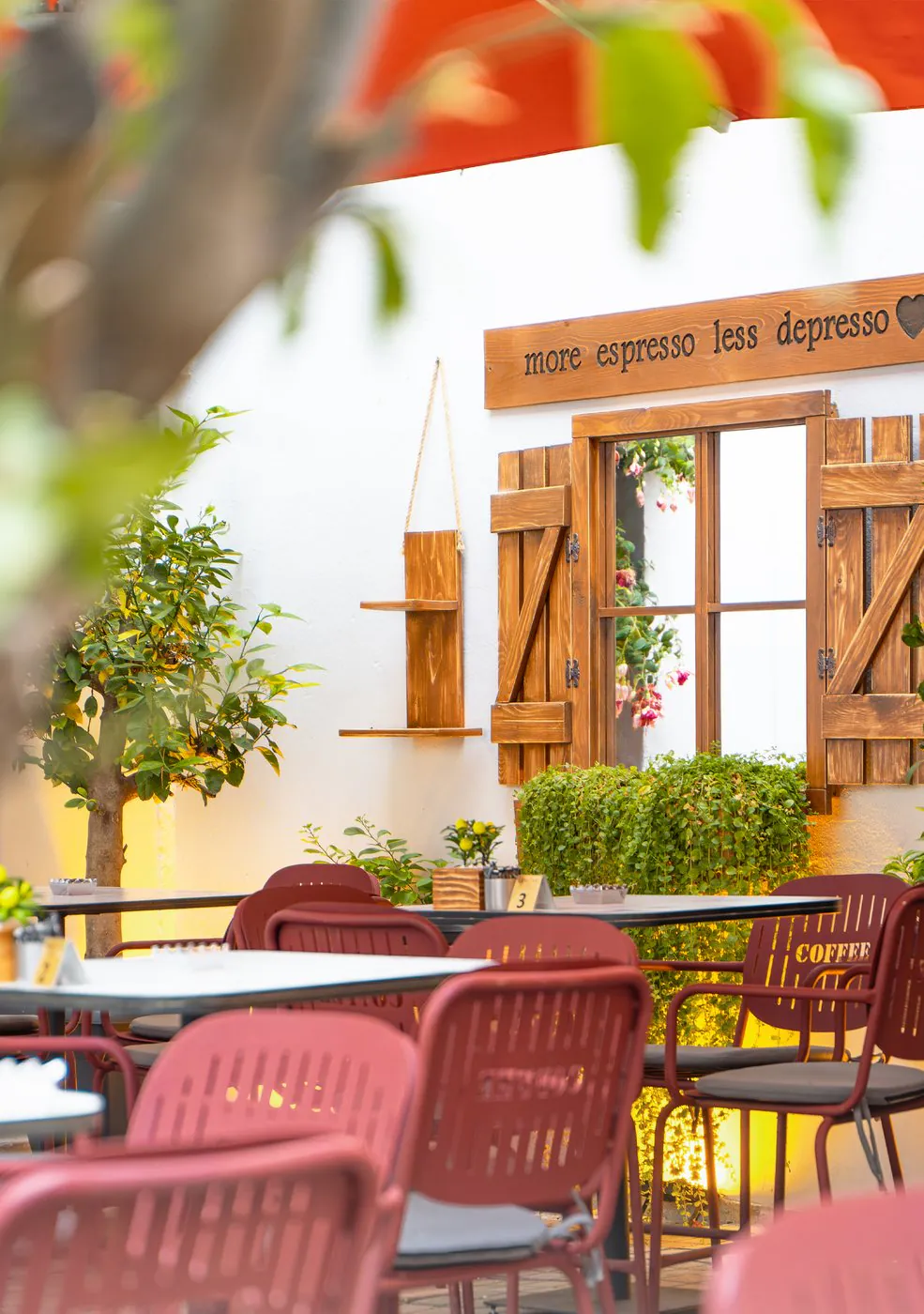 Lemon's Coffee — Red chairs, a lemon tree and the wall with wooden shutters