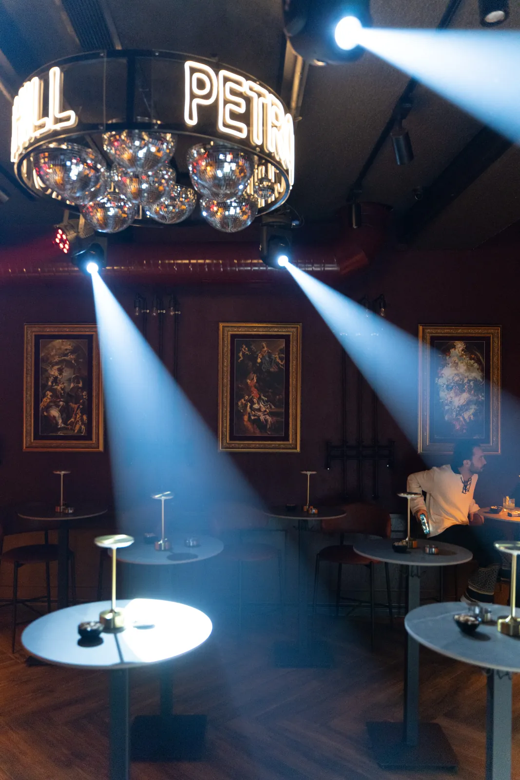 Petro Cocktail Bar — The lounge with blue light beams, the mirror-ball chandelier and classical paintings