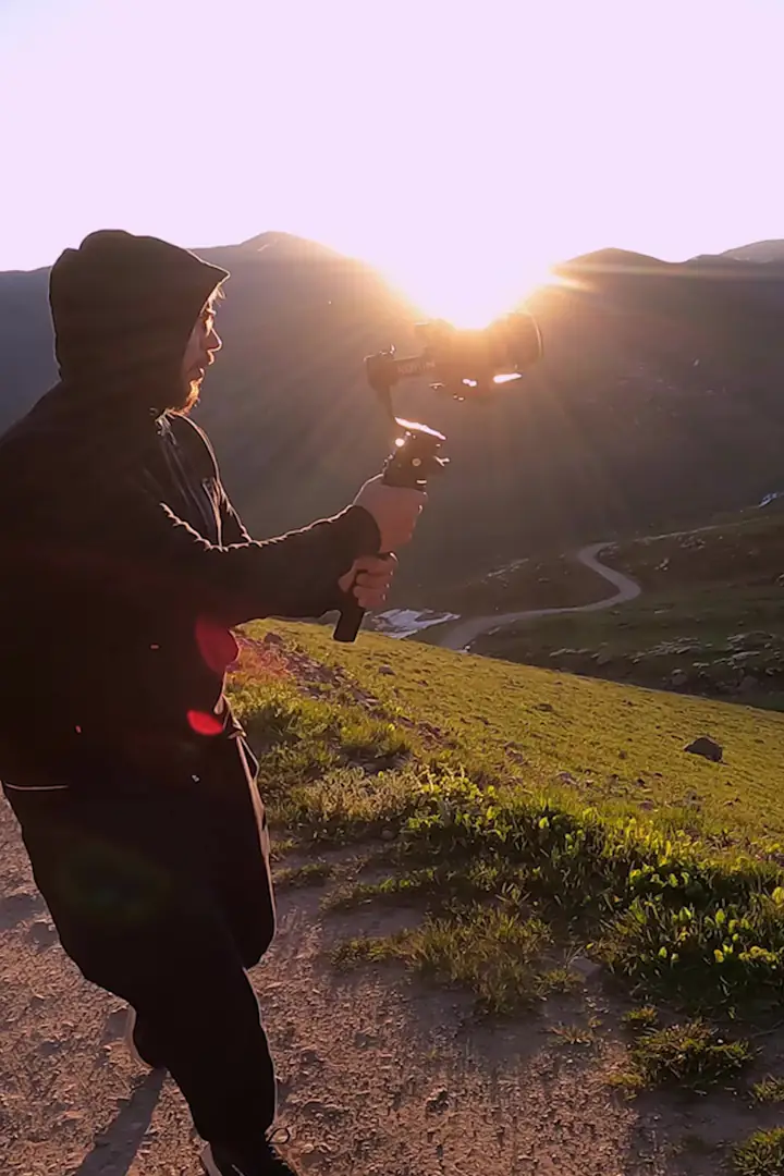 Gün doğumunda bir sırtta gimbal ile çeken operatör